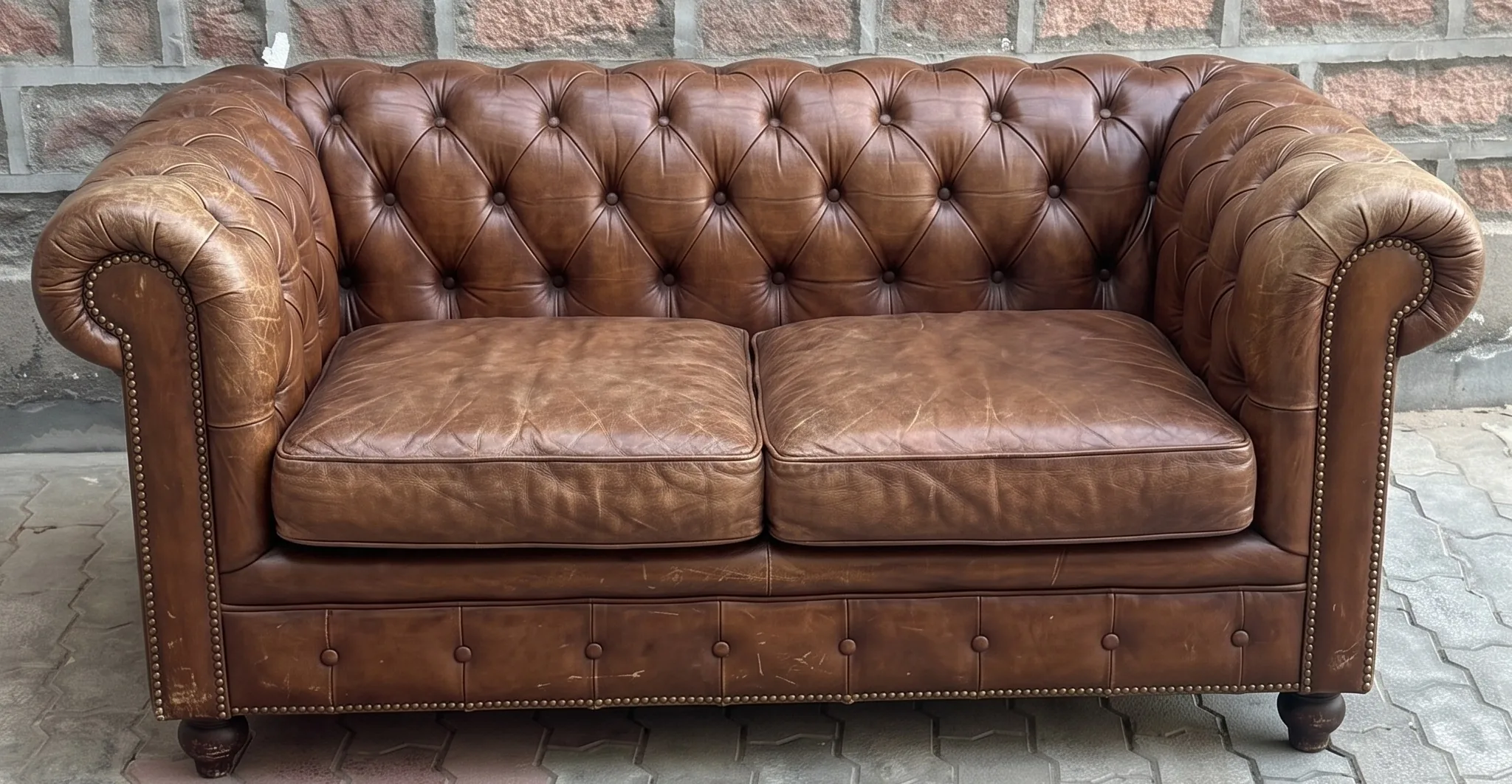 Faded, dry brown Chesterfield sofa before restoration
